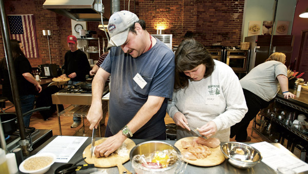 Bryant Harshbarger, left, and Mary Ruth Stephenson, right, work together as they cook up Haitian-style chicken and rice during a cooking class at the Huntington’s Kitchen.