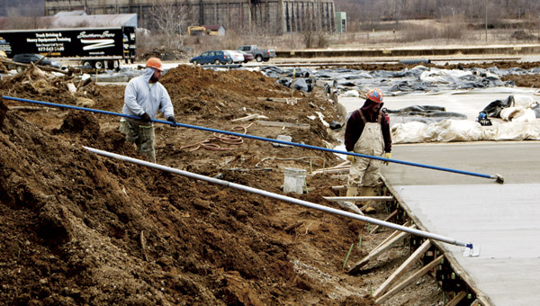 Workers from Boone Coleman Construction of Portsmouth smooth out wet concrete on a roadway built at The Point industrial park. The road is to provide access to Intermountain Electronics’ new facility at the park. After the concrete was poured, the crews covered the sections with heat blankets to allow it to set up.