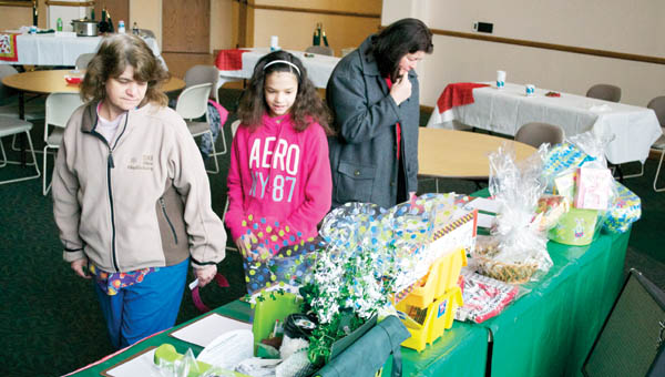 Faye Hammond, left, and her daughter Jazmine, center, check out themed gift baskets up for bid for a silent auction that was held as part of the ACTION Psychology Club’s annual Chili Cook-off Thursday in the Ohio University Southern Riffe Rotunda in Ironton.