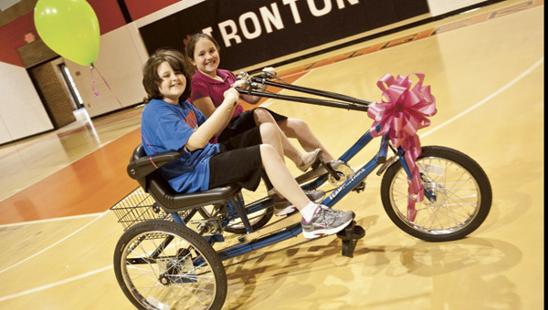 Katie Scott rides her new two-seat bike with Meredith Humphreys Thursday at the Conley Center. Scott, who just turned 10 years old, received the bike as part of a fundraising effort by students which has caused her to lose sight. Katie was diagnosed with a brain tumor at seven months old.