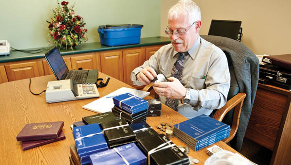 Rich Giedroyc a numismatist with HCC Inc., a rare coin management company, evaluates a large collection of coin sets, Liberty dollars, silver dimes and nickels along with collectors medallions and much more to determine their value Tuesday afternoon at WesBanco in Proctorville.