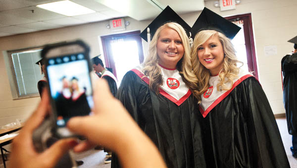 Alexis Mullins, left, and Emileigh Wilson, right, pose for photos before the start of commencement exercises Sunday at Dawson-Bryant High School.