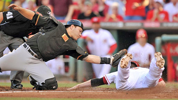 Cincinnati’s Zack Cozart (rght) is ruled out at home as Pittsburgh catcher Russell Martin attempts tag the runner and end the second inning. The Reds rallied and beat Pittsburgh 2-1 in 13 innings. (Photo Courtesy of The Cincinnati Reds)