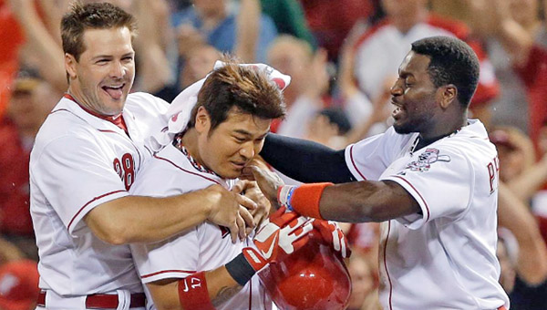 Teammates Chris Heisey, left, and Brandon Phillips, right, mob Shin-Soo Choo after his two-out single in the 11th inning drove home the winning run as the Cincinnati Reds beat the San Francisco Giants 3-2 on Wednesday. (Photo Courtesy of the Cincinnati Reds)