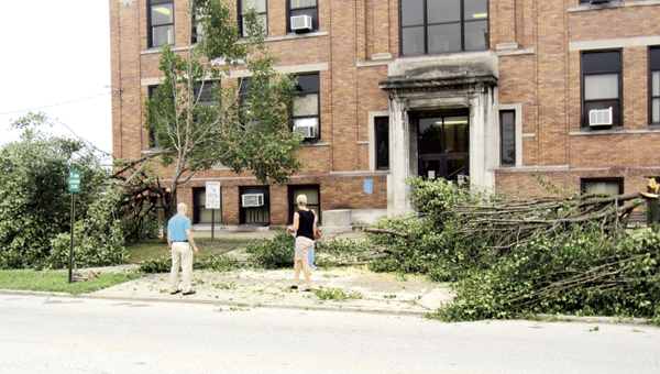 Tim Nunnery, Lawrence County Board of Developmental Disabilities personnel and public relations director, left, assess the situation at Open Door School in Ironton after two trees snapped and blocked the school’s wheelchair access. Dan Dillon, a member of the school’s maintenance crew, right, cleans up limbs.