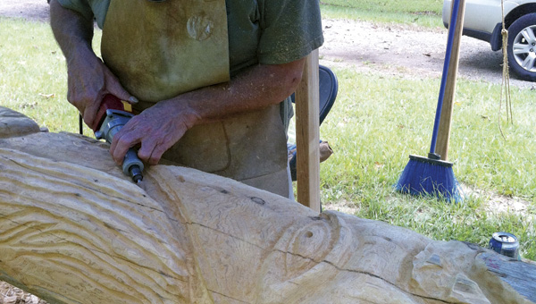 Woodworker Charlie Cook carves Native American symbols into a 23-foot long pole. The totem pole will be erected on Saturday, Sept. 21, as part of the Camp Oyo Staff and Alumni Association Reunion and Open House.