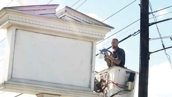 A painter from Young Signs of Ashland, Ky., paints the former Hallmark sign at the new Community Hospice office location on South Third Street in Ironton.