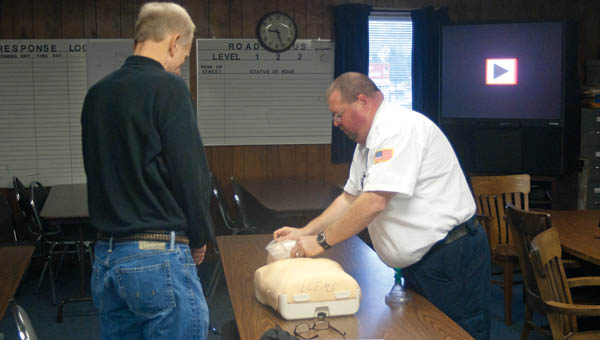 Ironton City Solicitor Bob Anderson, left, looks on as Lawrence County Emergency Medical Services Training Coordinator Steven Harrison, right, places a face barrier over a dummy as part of a Heartsaver CPR training class.