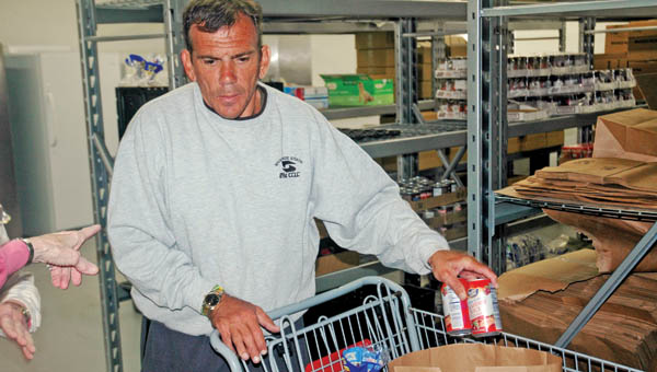 Michael Hampton arranges food in bags at Harvest for the Hungry food pantry in Ironton. Hampton spent two months homeless and now has an apartment, volunteers at the pantry and has joined church.