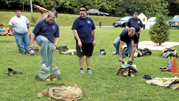 Alex Johnson of Upper Township Fire Department, left, and Austin Phillips of Harrison Fire Department in Gallipolis, right, compete in the firefighters’ challenge during the Public Fire Safety Day at Paul Porter Park in Coal Grove on Saturday. Jay Sherman, Coal Grove Fire Department captain, center, looks on.