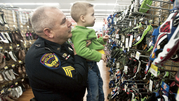 Officer Randy Thompson, with the Proctorville Police Department, gives little Acy Allen, 3, a lift to get a better look at a pair of shoes during the Shop with a Cop event at Wal-Mart Monday evening. Over 45 area children took part in the event.