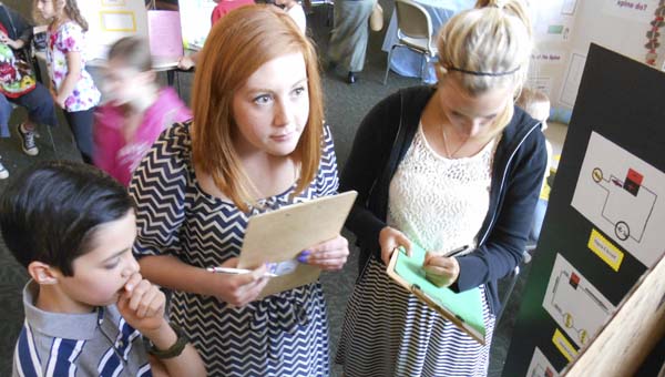 The Tribune/Brandon Roberts Benjamin Woodard, 11, explains his project, Electricity, to judges Haley Rickard and Katie Fuller during the 2014 Homeschool Science Fair at Ohio University Southern on Monday.