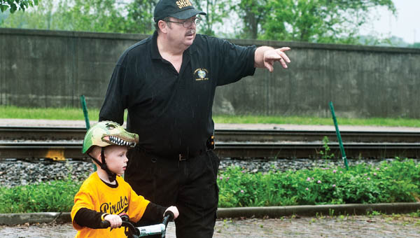 Corporal Ray Jones, with the Lawrence County Sheriff’s office, guides Jack Lambert, 5, through a bicycle obstacle course that teaches bike safety at the rodeo.