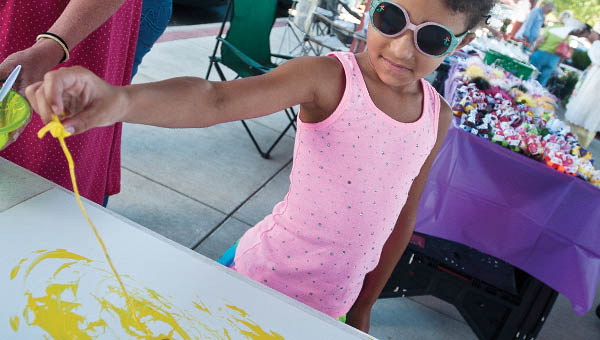 Seven-year-old Journey Blithe uses cooked spaghetti as her brush to create a painting while visiting the Ironton Farmers Market on Saturday.