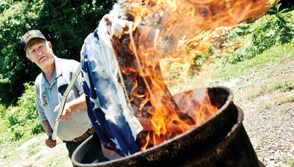 Warren Napier, Post Commander for VFW 6878 of Proctorville, participates in a flag-burning ceremony.