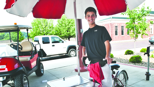 THE TRIBUNE/JESSICA ST JAMES Young entrepreneur Mason Slagel stands next to his cart at the Farmers Market in Ironton. Slagel put together his traveling cart of ice cream and pop to make extra money this summer.