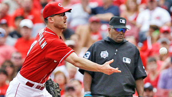 Just activated first baseman Jack Hannahan (left) flips the ball to pitcher Mat Latos who covers first base to record a putout in the fourth ininng of Sunday’s game. The Reds lost 4-2. (Courtesy of The Cincinnati Reds.com)