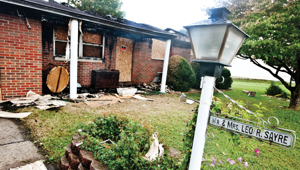 A sign depicting homeowners Mr. and Mrs. Leo R. Sayre hangs untouched while the home sits in ruins following a fire over the Fourth of July weekend.