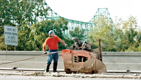Employees from Concrete Cutting and Breaking, Inc., of West Virginia, work on westbound U.S. 52 Thursday morning as a barrier wall is installed for future work on the lighting project.