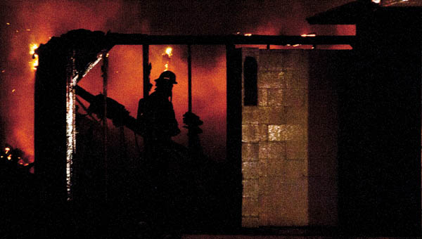 A firefighter from the City of Ironton is silhouetted by the flames of a late night fire on the grounds of the former Fuzzy Duck off of Center Street Tuesday evening. THE TRIBUNE/JESSICA ST JAMES