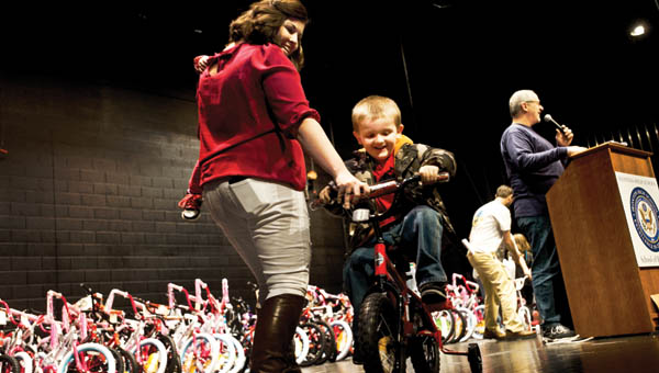 Emily Geswein helps Lycan Chapman after receiving his new bike during the Christmas Bike Giveaway Saturday.
