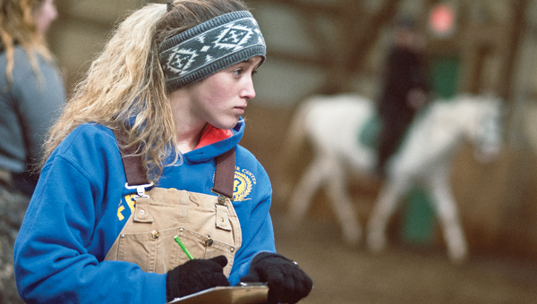 Patty Rife, student at Collins Career Center, watches students from the Ohio University Horse Park put the park’s horses through routines during a special equine class for high school students on Saturday.