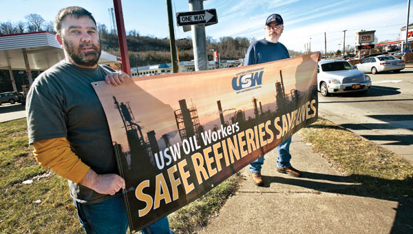 Mike Roark, left, and Curt Maynard, right, hold a sign at the corner of the Speedway gas station along 13 Street in Ashland as they and other Marathon Petroleum employees continue their protest efforts.