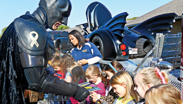 Batman, also known as John Buckland, meets with students at Burlington Elementary School on Monday to give out smoke detectors.