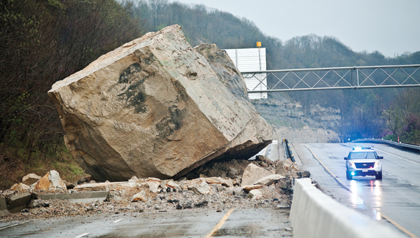 An Ohio State Highway Patrol cruiser looks small compared to the two-story boulder blocking U.S. 52 on Friday morning. The rockslide occurred around 3 a.m.