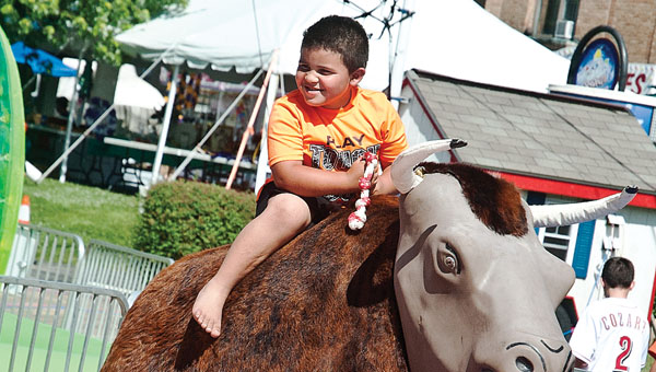 Five-year-old Jacarr Coleman attempts to ride the bull during the annual Charity Fair sponsored by the Ironton Catholic Schools.