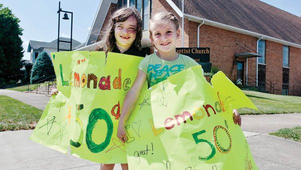 Seven-year-old Lori Belle Boyd, left, and Lexi Barnes, 6, sell glasses of homemade lemonade, on the corner of Fifth Street for a youth mission project at First Baptist Church in Ironton Friday.