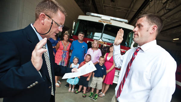 Ironton Mayor Rich Blankenship swears in Joe Laber as Ironton’s newest firefighter Friday while his family watches.