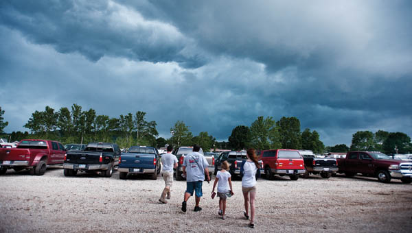 A family makes their way to their vehicle as storm clouds quickly roll in over the fairgrounds Monday.