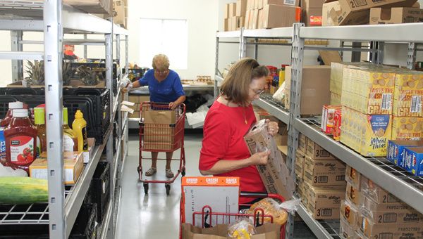 Ironton First United Methodist Church Harvest for the Hungry volunteers Bobbi Shelton (back) and Lil Hart gathering food for people Monday morning at the food pantry during a normal distribution.