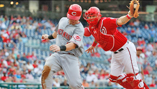 Cincinnati’s Tucker Barnhart scores a run in the eighth inning as he avoids the tag by Washington Nationals’ catcher Wilson Ramos. Barnhart singled earlier in the 8th inning for the Reds first hit against Max Scherzer. Cincinnati lost 5-1. (Photo Courtesy of The Cincinnati Reds.com)