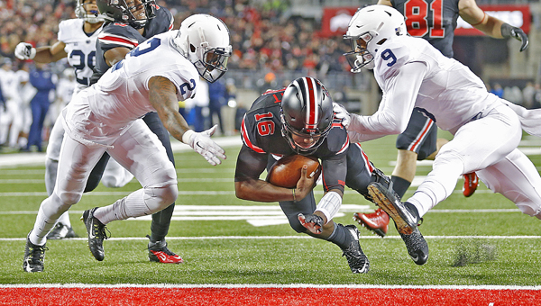 Ohio State quarterback J.T. Barrett (16) slides between Penn State safeties Jordan Lucas (9) and Marcus Allen (2) for a second-quarter touchdown at Ohio Stadium in Columbus, Ohio, on Saturday, Oct. 17, 2015. (Chris Russell/Columbus Dispatch/TNS)