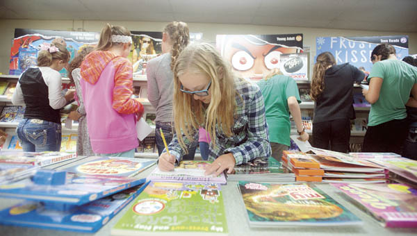 Kaitlyn Fleming makes a list of books she would like to buy during the annual book fair at Fairland Middle School.