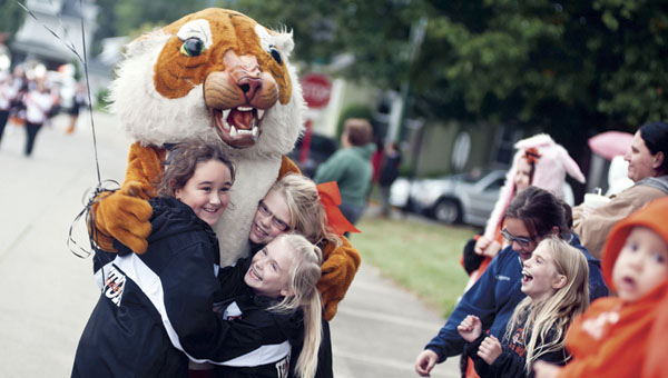 Taylor Vanderhoof, Emily York and Daizy Meadows give the Ironton High School Tiger mascot a big hug during the first homecoming parade Thursday along Bob Lutz Way.