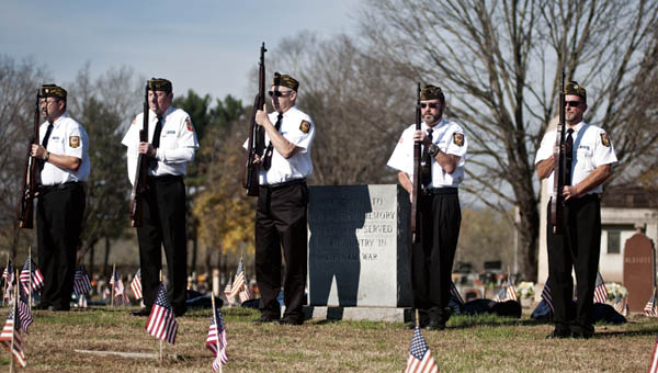 Members of the VFW 8850, Ironton Post, stand at attention. (BELOW) Rob Curnell holds the flag during the Veterans Day service at Woodland Cemetery on Wednesday.