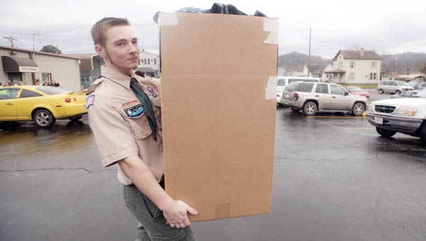 Wyatt Boggs, with Boy Scout Troop 106, helps deliver boxed goods to cars during a giveaway event at the City Welfare Mission Wednesday in Ironton.