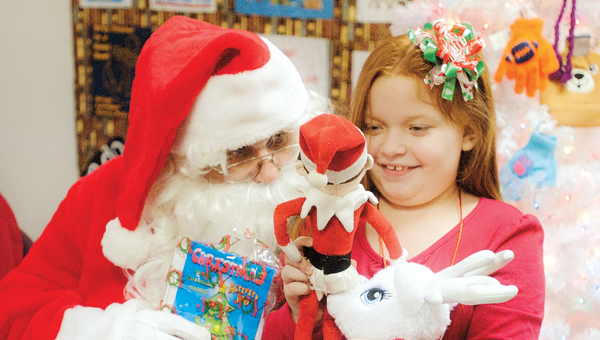 Lilly Bowman shows off her Elf on the Shelf while visiting with Santa Claus at the Briggs Lawrence County Library Chesapeake Branch Tuesday evening.