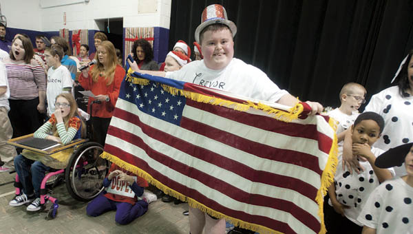 Trevor Hall stands proudly holding the American flag as students and faculty perform “Let There Be Peace On Earth” for the finale of the Open Door School “A Disney Christmas” on Tuesday.