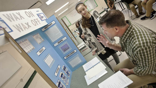 Judge Dan Webb speaks with student Blake Anderson on his project of “Wax On Wax Off” at the Fairland Middle School science fair Wednesday.