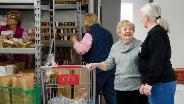 Volunteers Doris Collins and Lois Terkhorn speak in the stock room of Harvest for the Hungry food bank in Ironton on Monday.