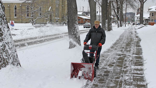 St. Lawrence School janitor Jim Monte snow blows the sidewalk in front of the school along Sixth Street in Ironton on Monday morning.