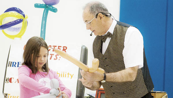 Second grade student Lily Stewart makes a balloon dog with magician Garry Boothe during a performance at Burlington Elementary School on Thursday.