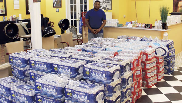 Antonio Murphy, owner of Only 1st Impressions barbershop, stands with cases of water donated for the people of Flint, Michigan. The shop started collecting water for Flint on Monday of last week.