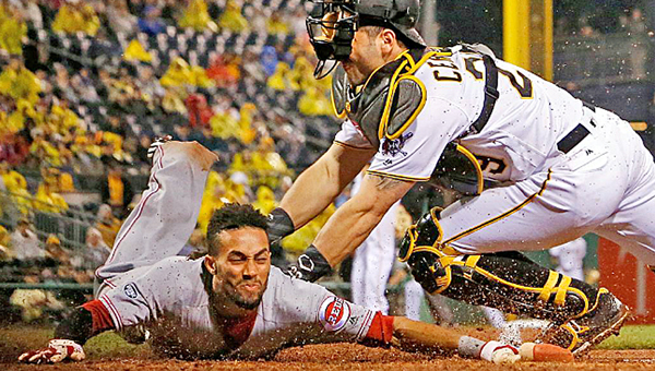 Cincinnati Reds’ Billy Hamilton (left) slides safely across home plate ahead of the tag by Pittsburgh Pirates’ catcher Francisco Cervelli in the fifth inning. The Reds beat the Pirates 6-5 in 11 innings on Sunday. (Courtesy of the Cincinnati Reds.com/Gene J. Puskar (AP))