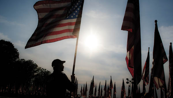 Participants begin to set up the flags for the Ohio Flags of Honor display following Friday evening’s ceremony at Ironton Hills Plaza.