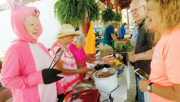 Lois Terkhorn, left, greets guests to the Harvest for the Hungry Booth as she and other volunteers raise money for the food pantry Saturday at the Ironton Farmers Market.